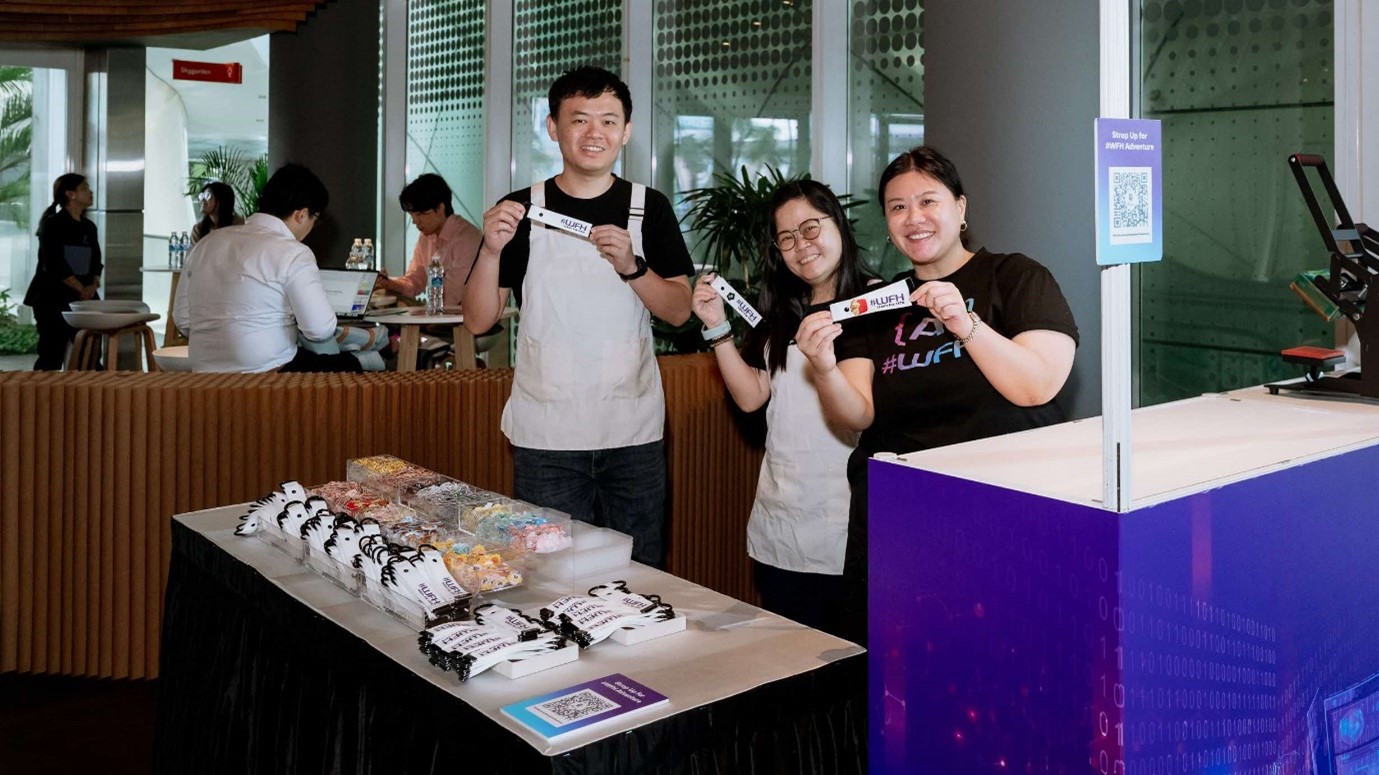 3 people at a booth holding up souvenir straps.