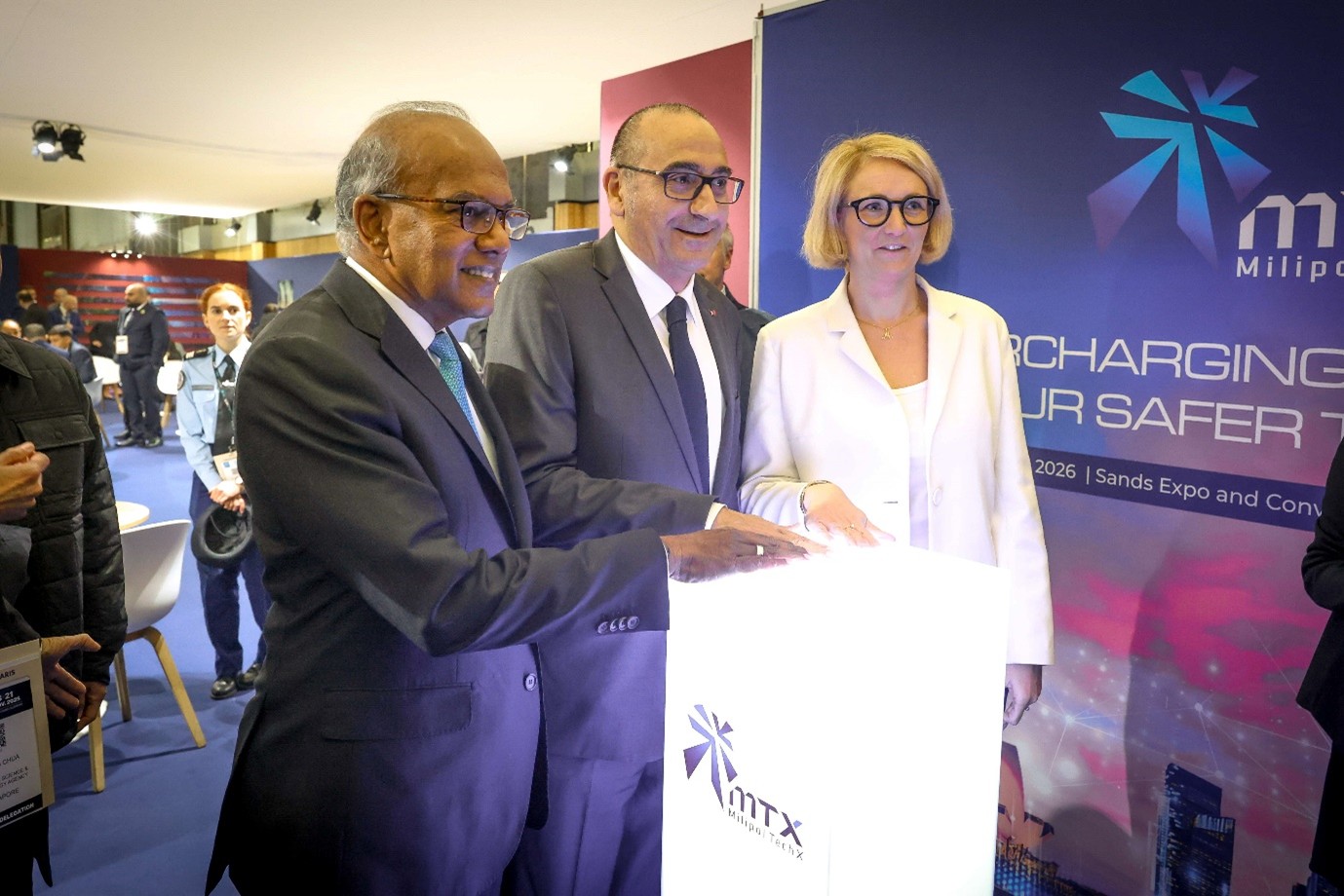 Three people stand next to a white box with their hands on it.