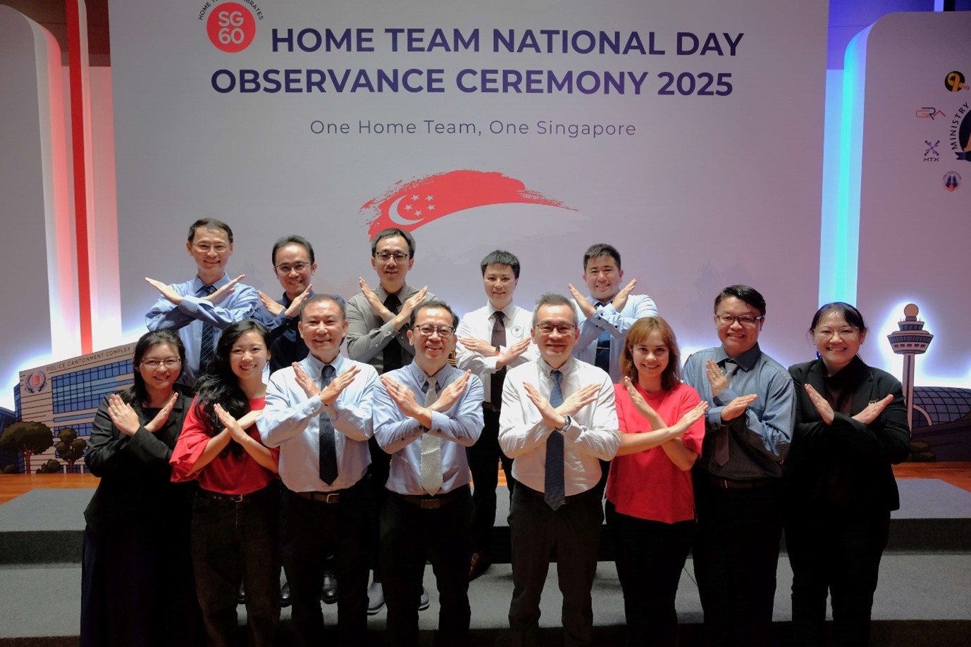 A group of people standing on stage with their hands crossed in an ‘X’ pose.