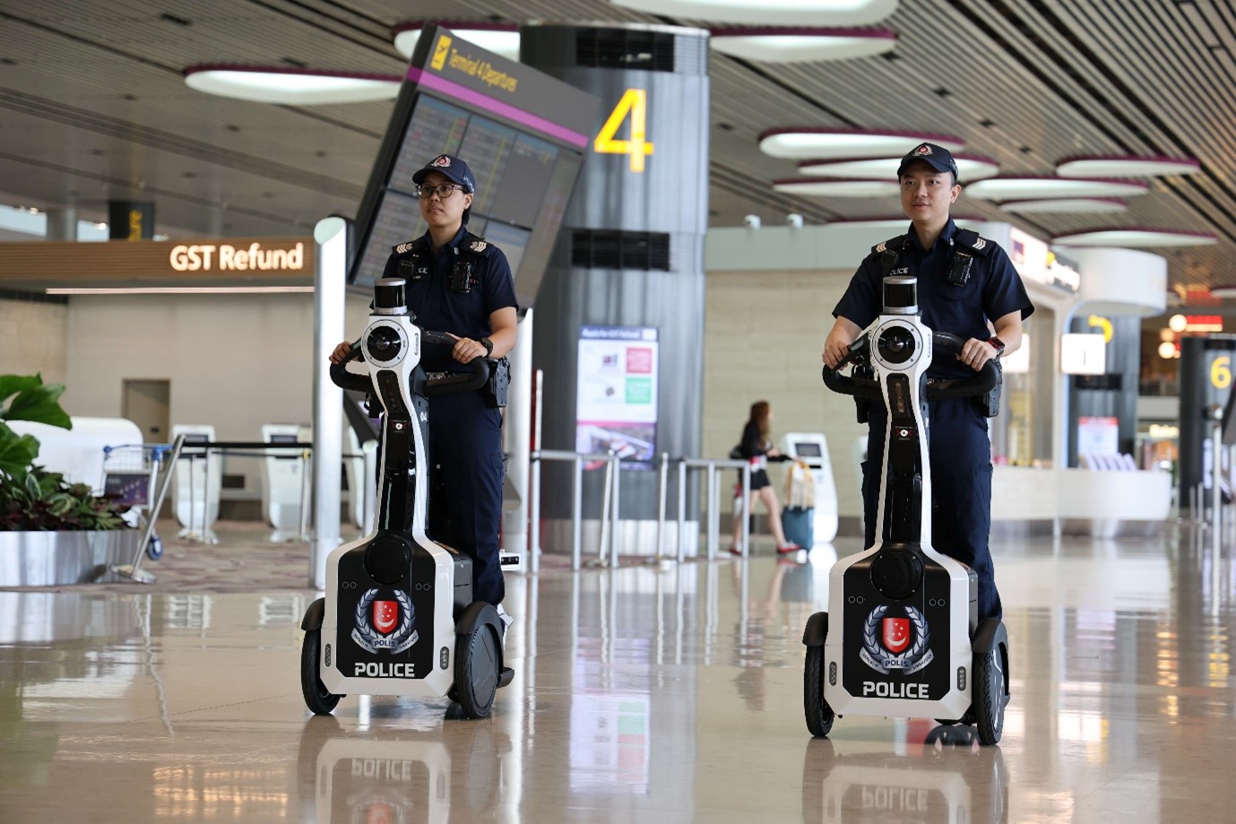 Two police officers riding two wheeled autonomous robots.