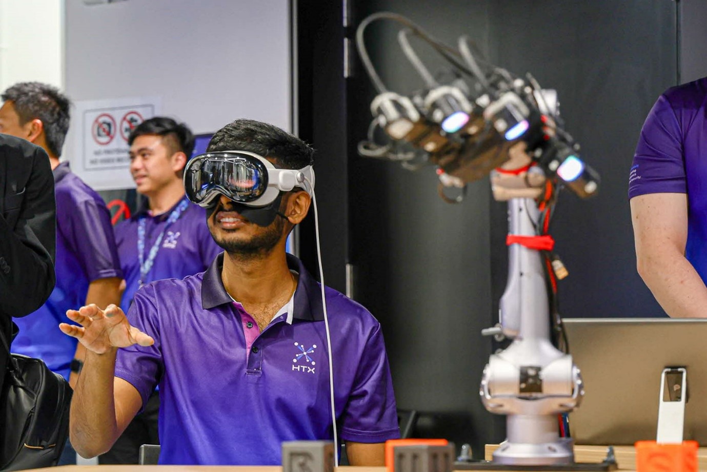 A man wearing goggles and standing in front of several robotic machines.