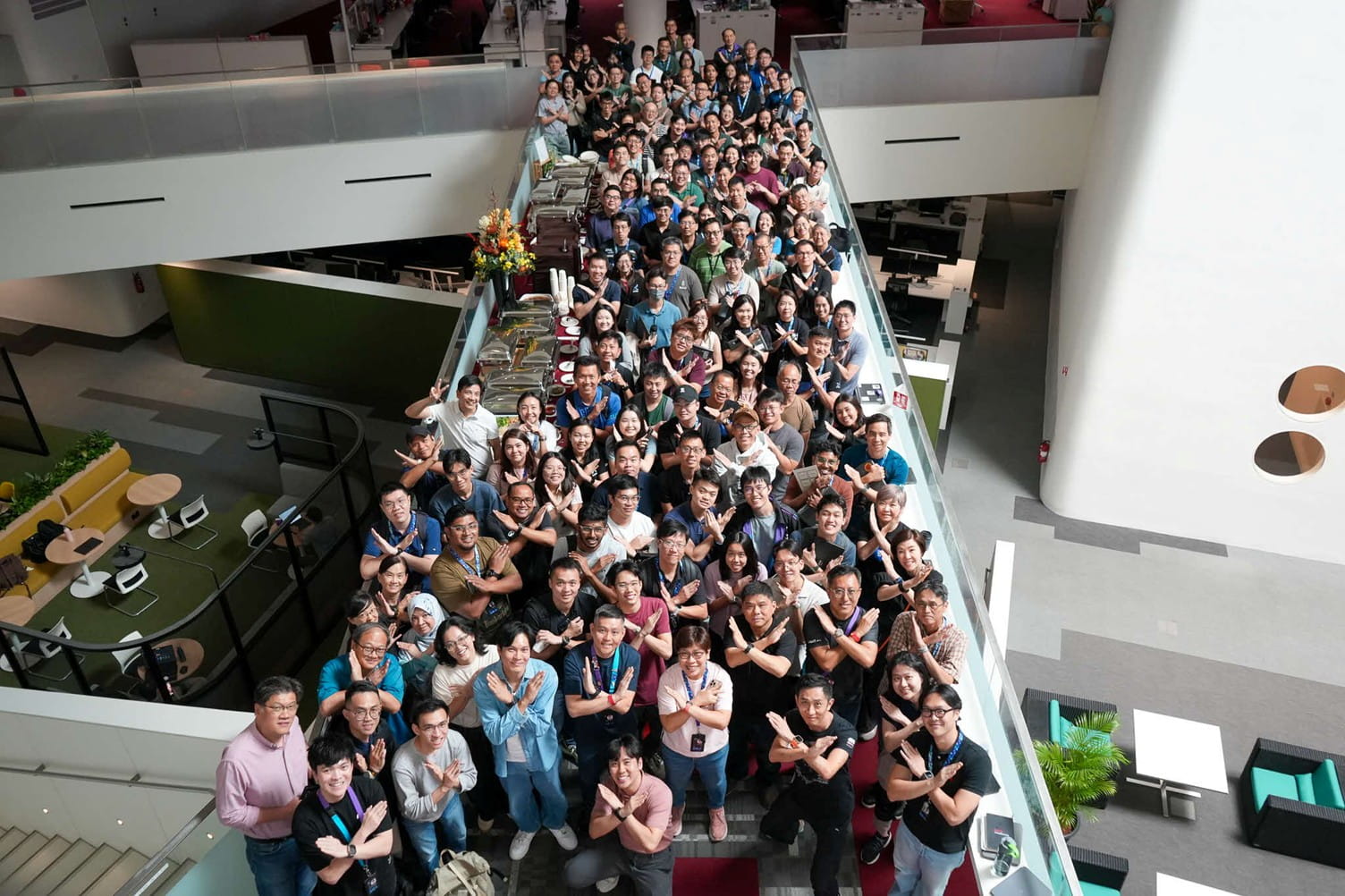 Large group of people standing closely together on an indoor link bridge.