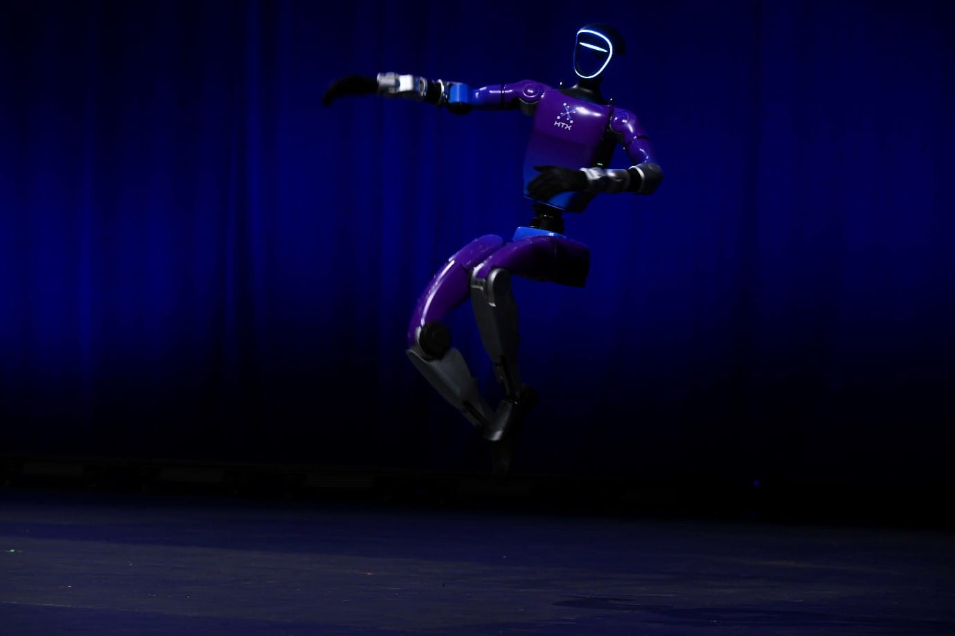 A humanoid robot performing a dance move on stage.