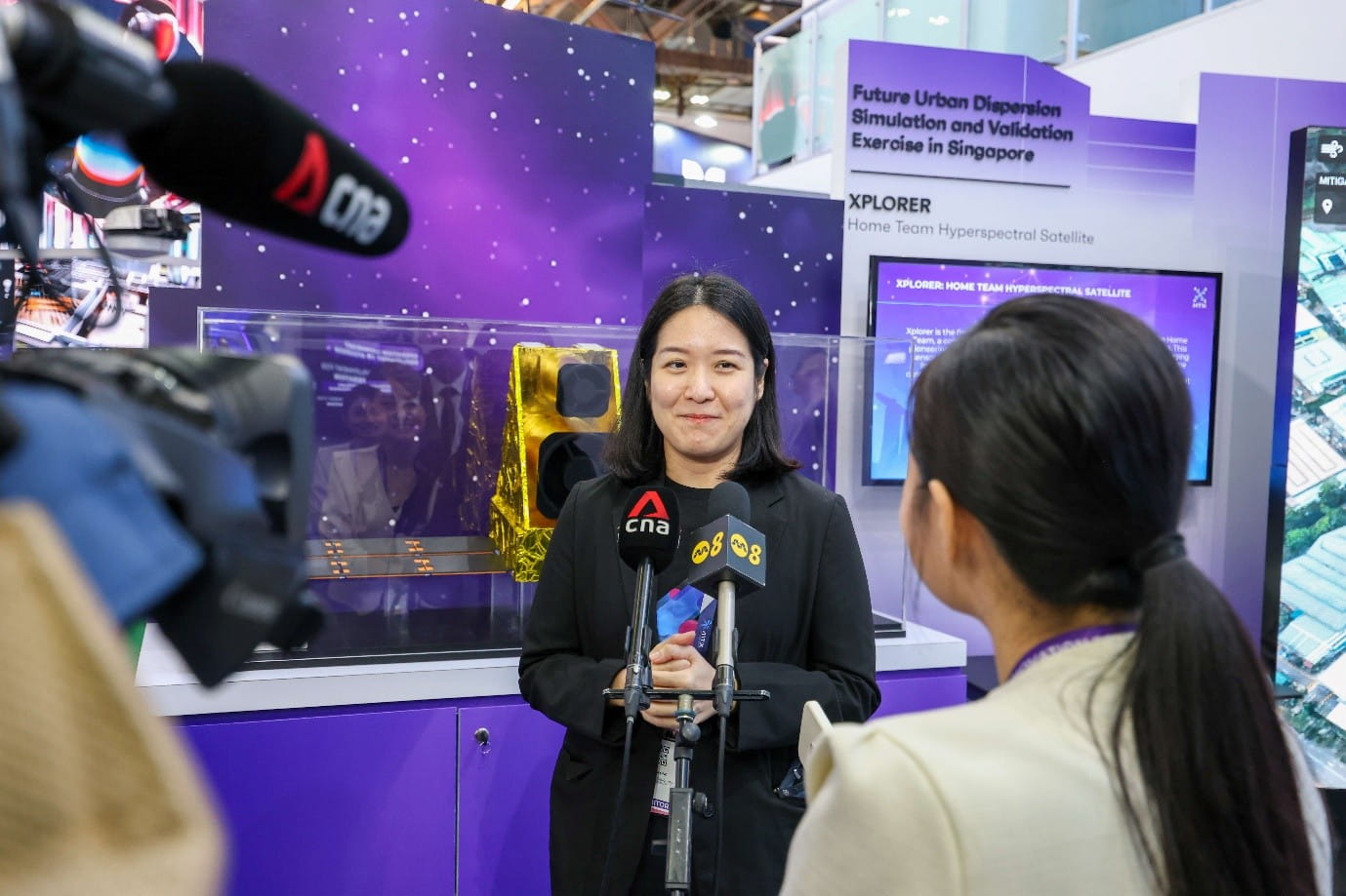 Woman being interviewed by reporters at a tech exhibit.