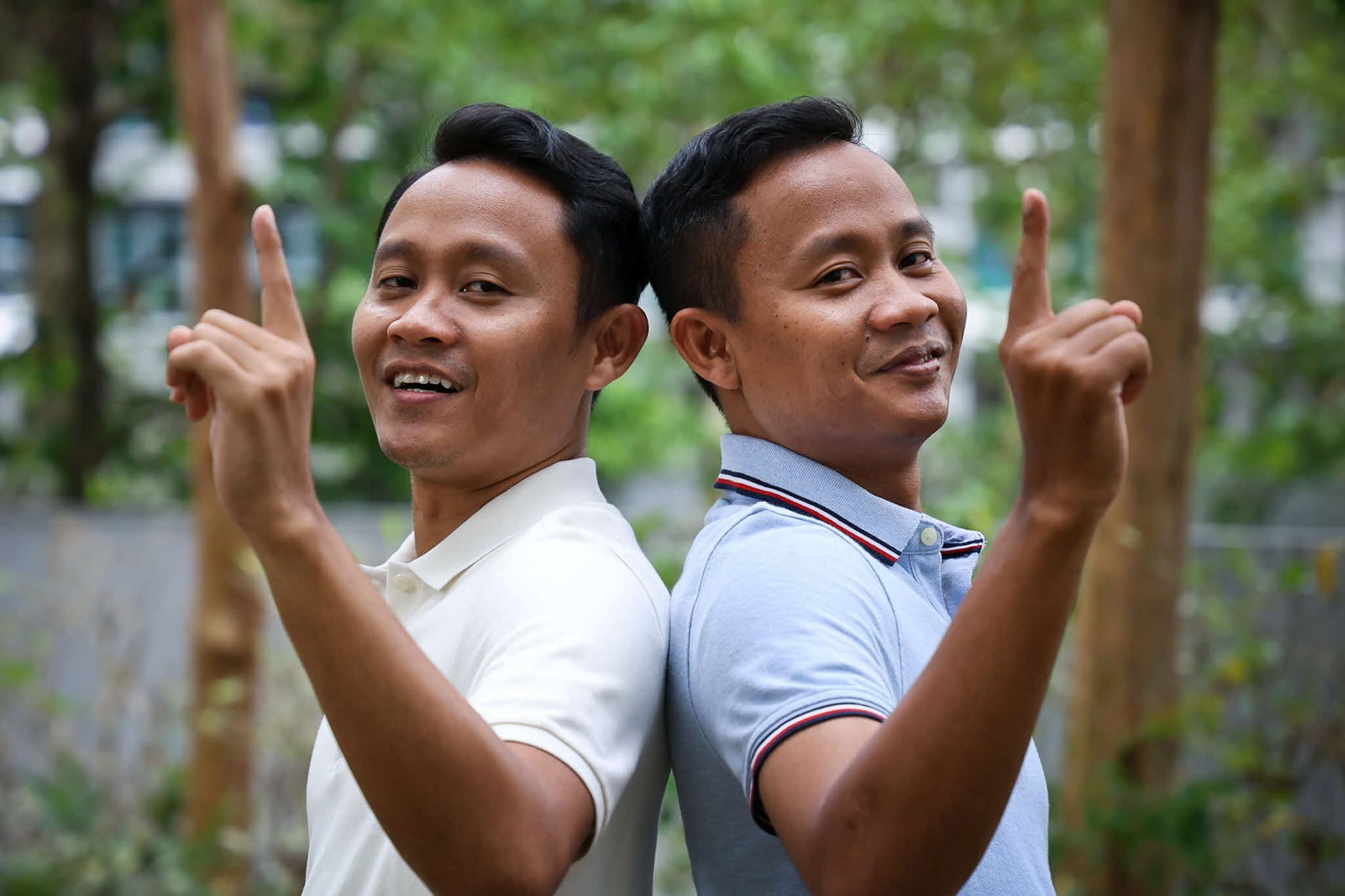 Two men standing back-to-back outdoors.